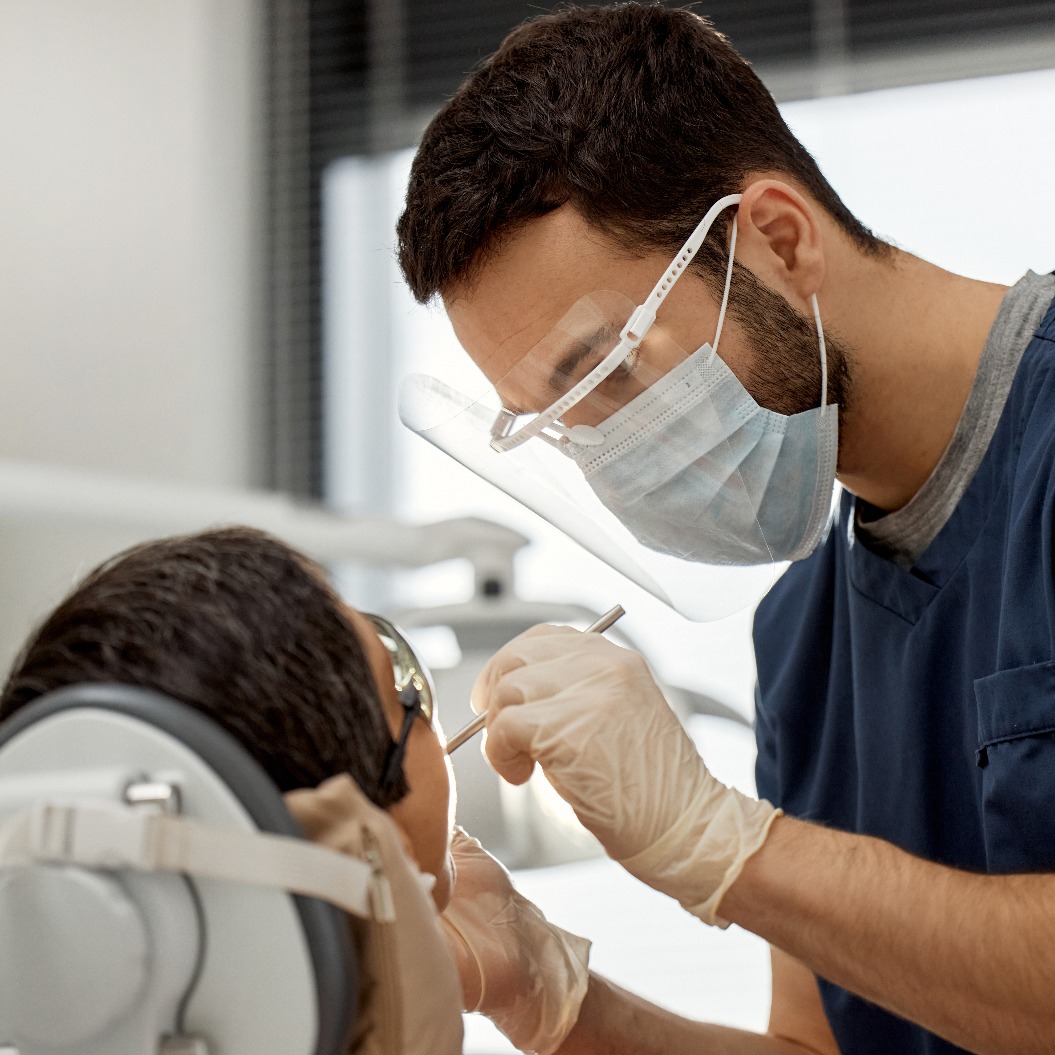 Ein junger Zahnarzt untersucht einen Patienten während eines Zahnarzttermins