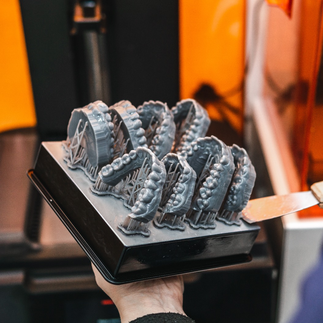 Ein Zahntechniker entnimmt Kiefermodelle aus einem 3D-Drucker im Labor. Modell für Zahnersatz
