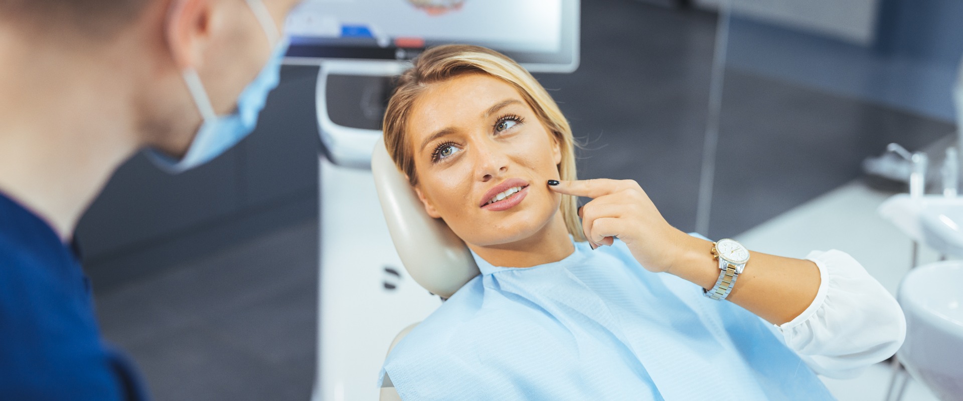 Nahaufnahme eines professionellen Zahnarztes mit chirurgischer Schutzmaske, der eine Untersuchung an einem Patienten durchführt. Zahnarzt untersucht eine lächelnde Patientin in der Praxis. Ein Mann untersucht eine lächelnde Patientin im Untersuchungszimmer.