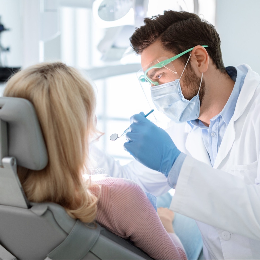 Ein Zahnarzt mit Gesichtsmaske und Brille bei der Behandlung